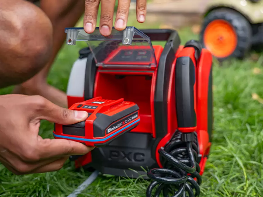A person inserts a Power X-Change battery into the protected battery compartment of the Einhell cordless pressure cleaner TE-HP 18/10 Li D-Solo.