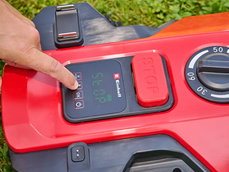 Un dedo toca la pantalla del Einhell robot cortacésped FREELEXO 1000 para su manejo.