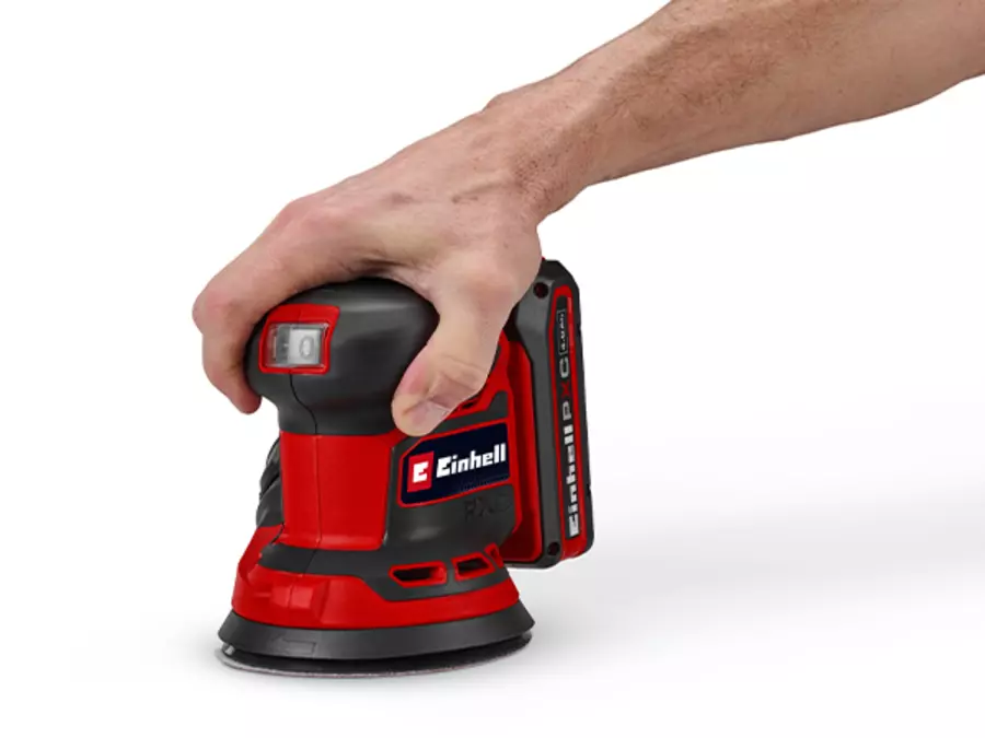 A hand grips the ergonomic soft-grip handle of the Einhell cordless orbital sander TE-RS 18/28 Li - Solo on a white background.