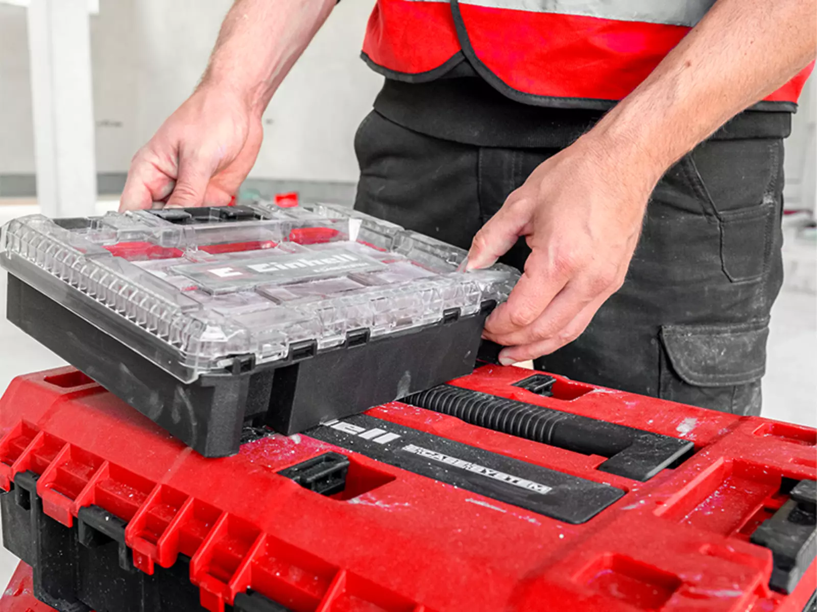 Einhell E-Case S-F SEALED with inserted half-size box being placed onto the case by two hands.