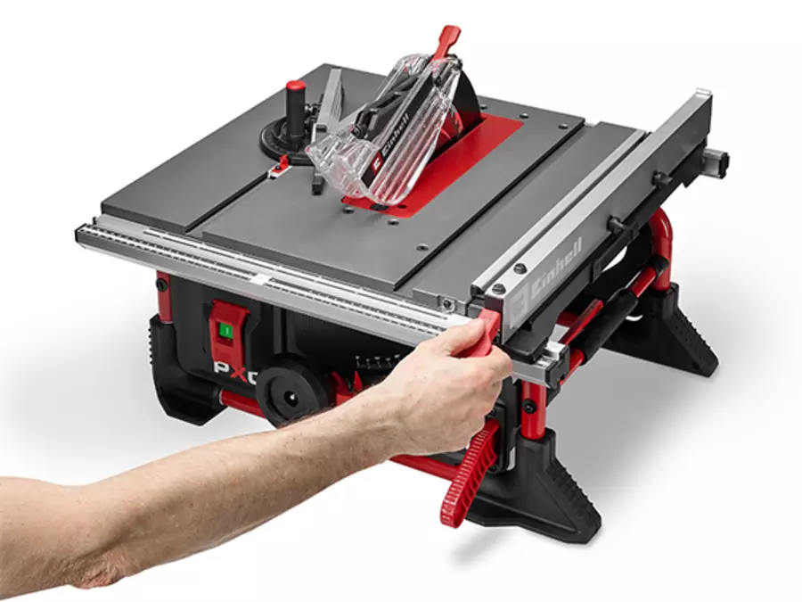 Die Einhell Akku-Tischkreissäge TE-TS 36/8 T Li-Solo mit eingestelltem Parallelanschlag und einer Hand, die den Anschlag führt.