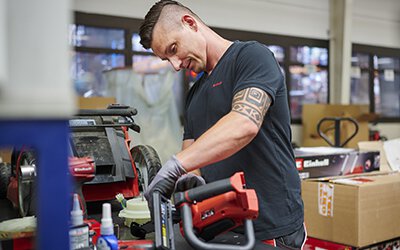 Τechnician performing hands-on repair on a power tool in a workshop environment, representing professional repair service.