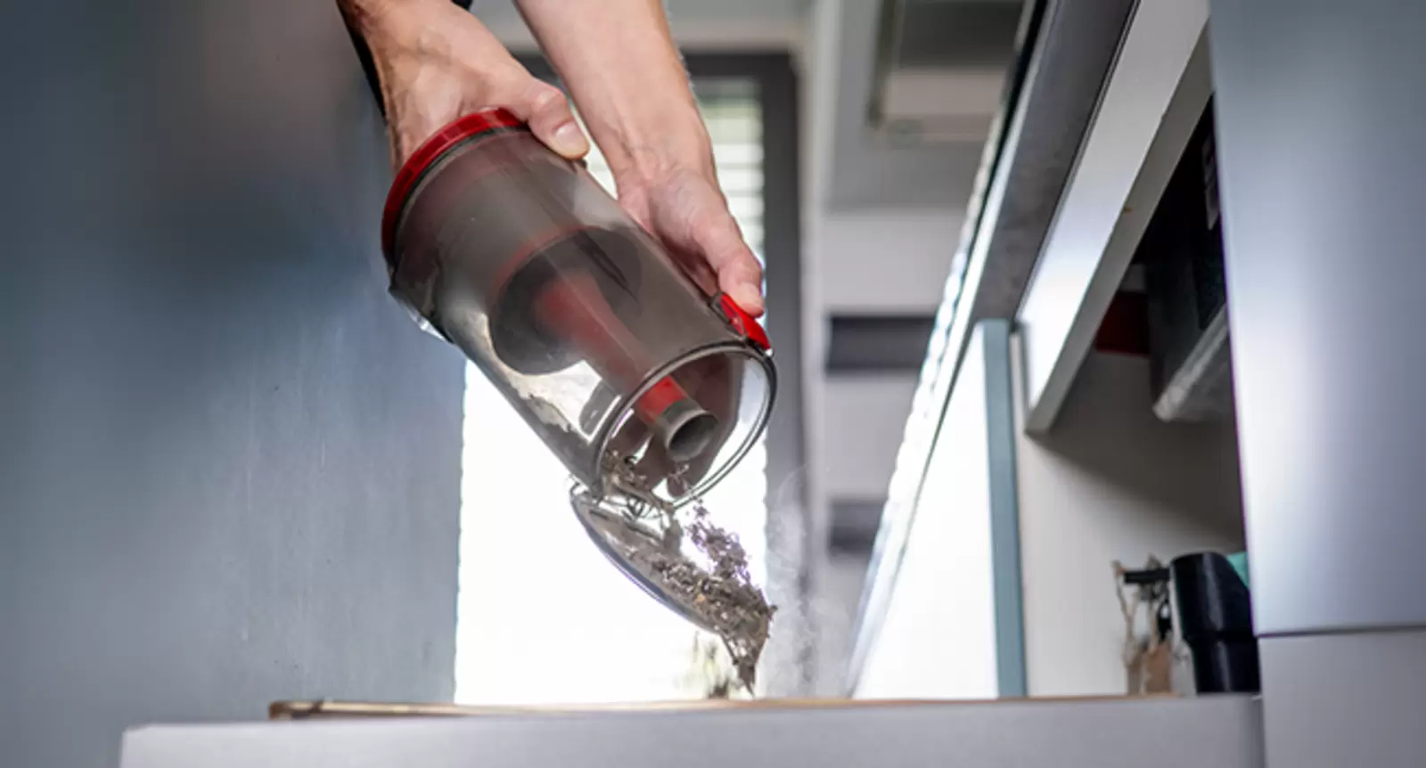 Eine Person entleert den beutellosen Schmutzbehälter des Einhell Akku-Stielstaubsaugers TE-SV 18/270/1 Li BL-Solo per Knopfdruck.