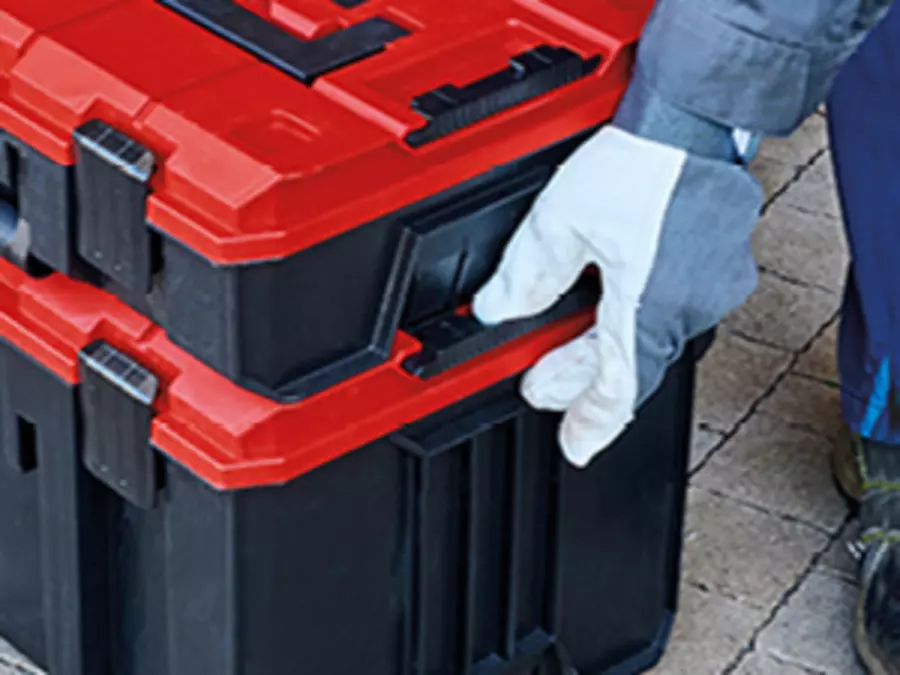 Gloved hand locks two red Einhell tool cases using the integrated connection system.