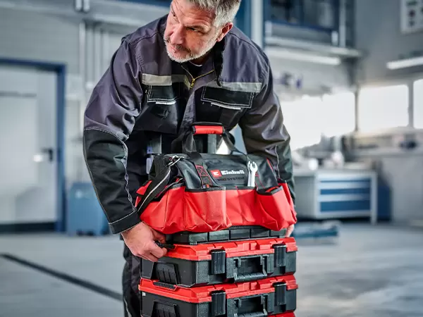 Person carrying the Einhell Pro System Tool Bag using the integrated top carry handle.