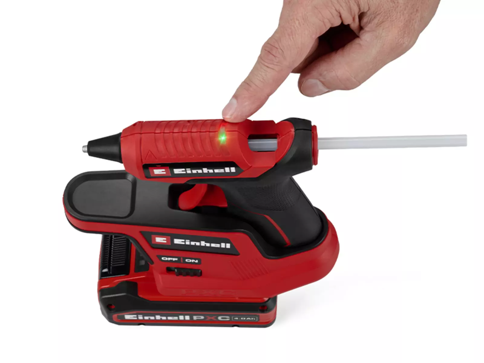 One hand points to the green LED of the Einhell cordless hot glue gun TE-CG 18/7 Li, signalling that the device is ready for operation.