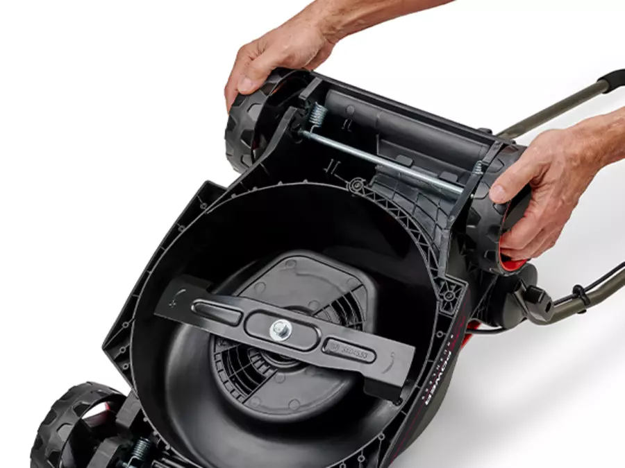 Bottom of the Einhell cordless lawn mower GE-CM 18/30-1 Li BL-Solo with view of the mowing mechanism; hands adjust the axial cutting height.