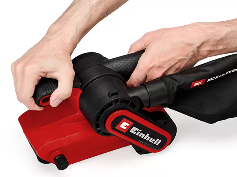 Une personne tient la ponceuse à bande Einhell TC-BS 800 à deux mains par les surfaces Softgrip.