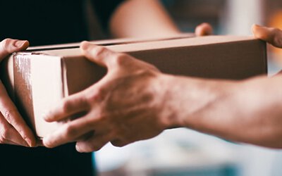 Close-up of hands exchanging a cardboard box, symbolizing free collection and shipping for warranty claims.