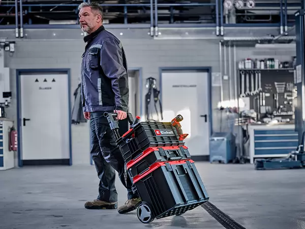 Person pulling a stacked Einhell Pro System storage setup mounted on a wheeled trolley.