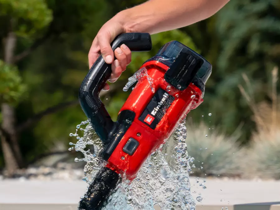 Der Einhell Akku-Poolsauger GE-PV 18/42 Li T-Solo wird am ergonomischen Handgriff hochgehoben, Wasser tropft ab.
