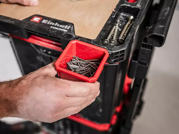 A red storage container with nails is inserted into a holder on the Einhell E-Case worktop.