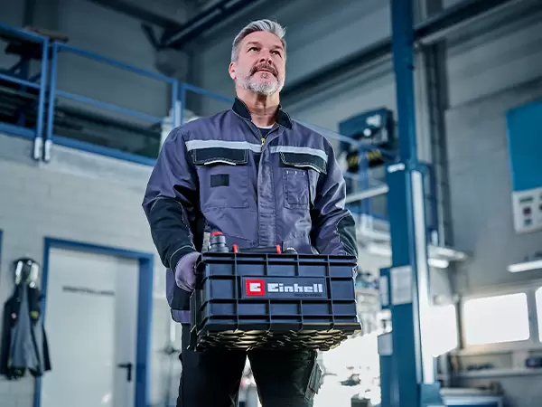 Person carrying the Einhell Pro System Toolbox using the two integrated side handles.