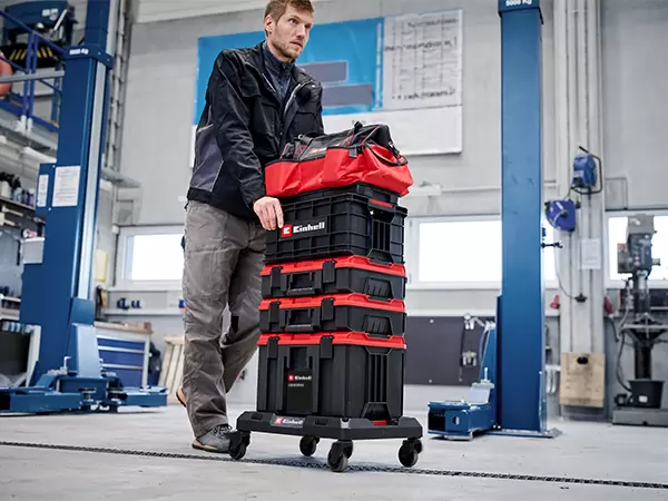 Person pushing a stacked Einhell Pro System storage system on the Einhell Pro System Dolly through a workshop.