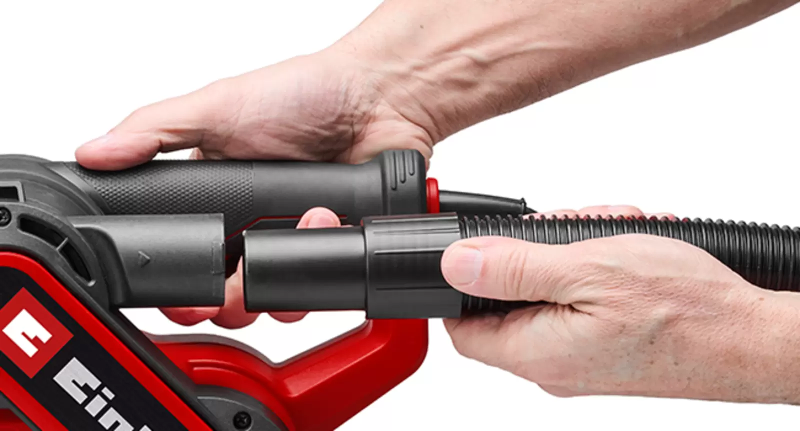 Une personne raccorde le tuyau d’un aspirateur eau et poussière à l’adaptateur d’aspiration de la ponceuse à bande Einhell TC-BS 800.