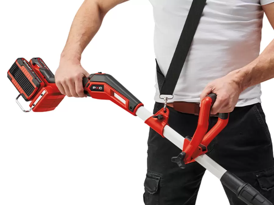 Bir kişi, Einhell GE-CT 36/35 Li BL-Solo Akülü Kenar Kesme Makinesini omuz askısını kullanarak taşır.