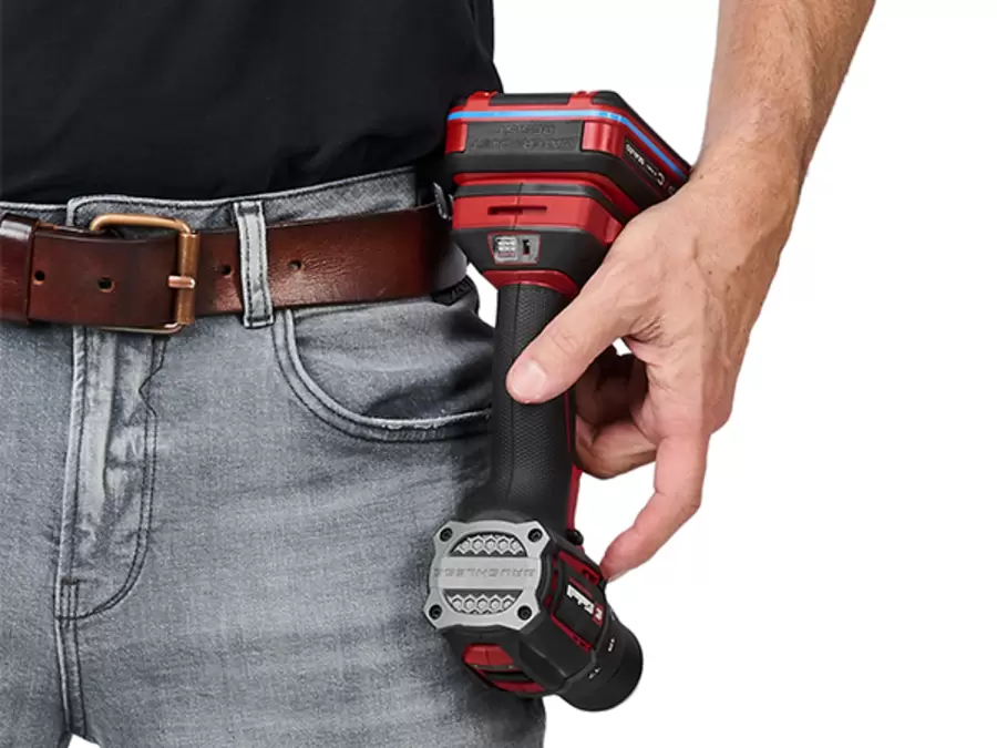 The Einhell Professional Cordless Impact Drill Driver TP-CDD 18/501-C Li-i +70 (3Ah) hangs from a person’s belt using the belt clip.