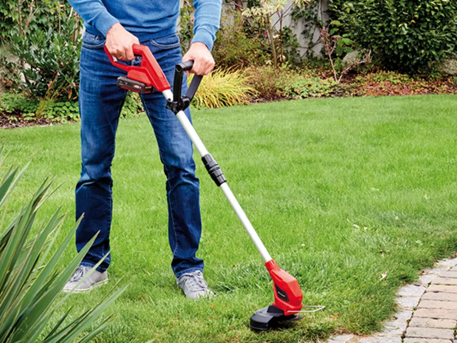 A man trims lawn edges in the garden with the Einhell cordless grass trimmer GC-CLT 18/240 Li - Solo.