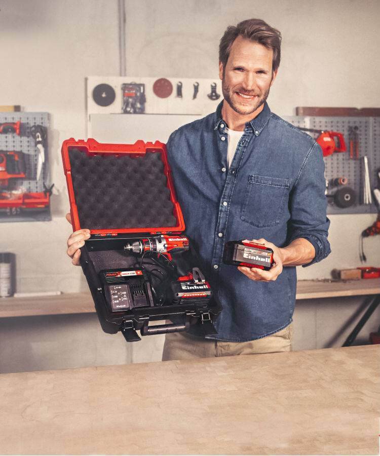 Batteries and chargers – Man presenting an Einhell battery kit with charger