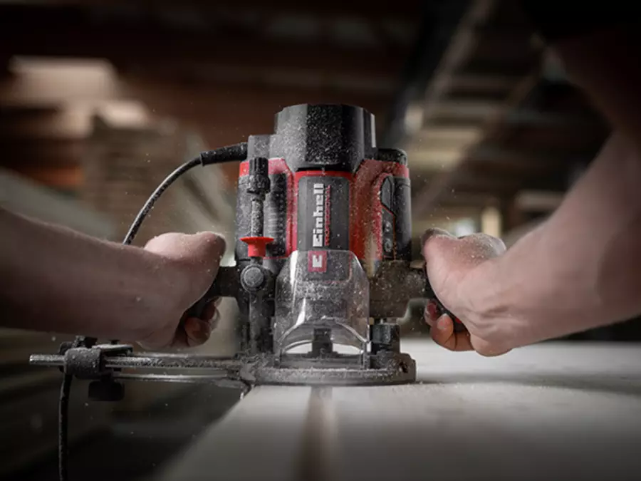 The Einhell TP-RO 1400 E router in use, both hands guide the tool safely for ergonomic working.