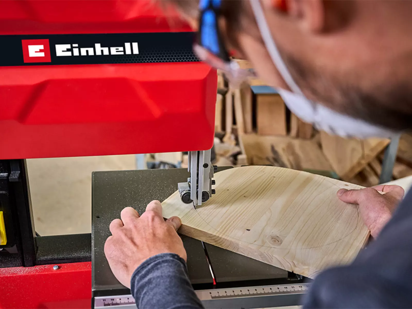 A person is cutting a round wooden board in a workshop using the Einhell band saw TC-SB 245/1 L.