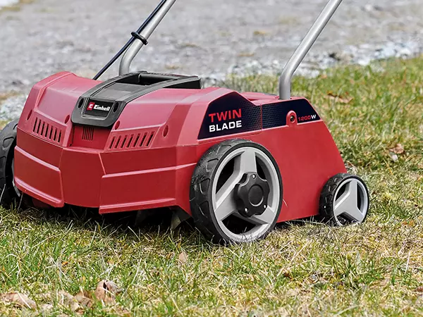 Der Einhell Elektro-Vertikutierer GC-ES 1231/1 seitlich von schräg hinten gezeigt mit Fokus auf Räder und Gehäuse.