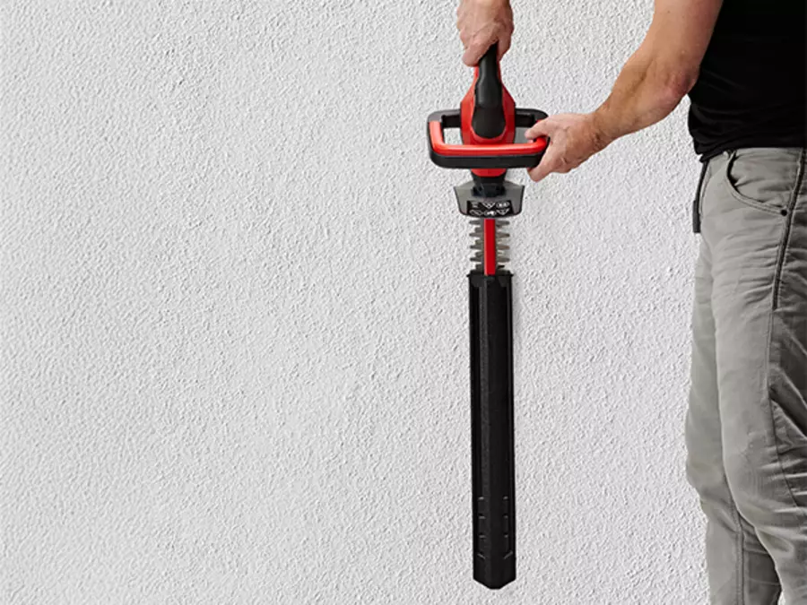 The Einhell cordless hedge trimmer GC-CH 18/40 Li Kit with attached blade cover is held vertically.