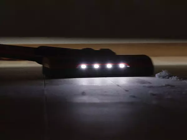 LED lights on the floor nozzle of the Einhell cordless stick vacuum cleaner TE-SV 18 Li while vacuuming on a dark surface.
