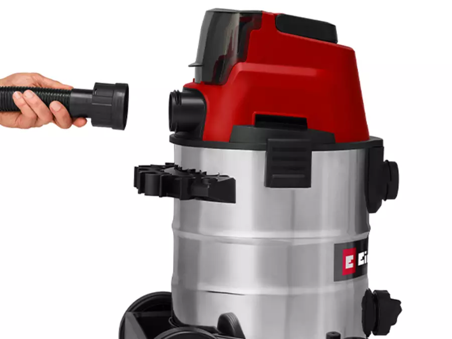 A hand connects the suction hose to the blower port on the back of the vacuum cleaner.