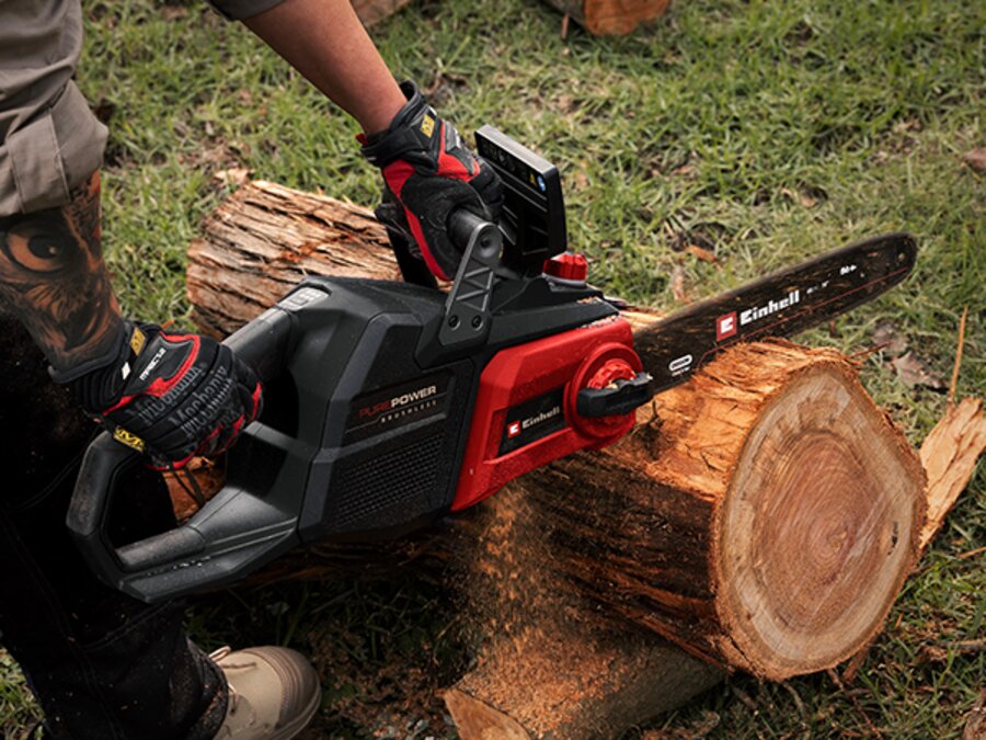 Person cutting a tree trunk with the Einhell Professional 36V Brushless 400mm Chainsaw.