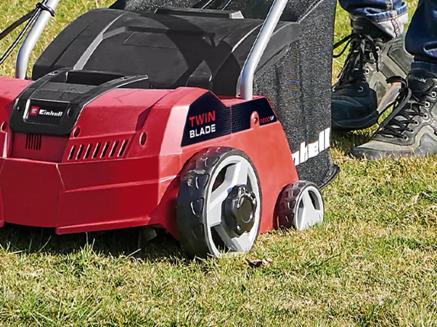 Der Einhell Elektro-Vertikutierer-Lüfter GC-SA 1231/1 mit montiertem Grasfangkorb aus schwarzem Netzmaterial.