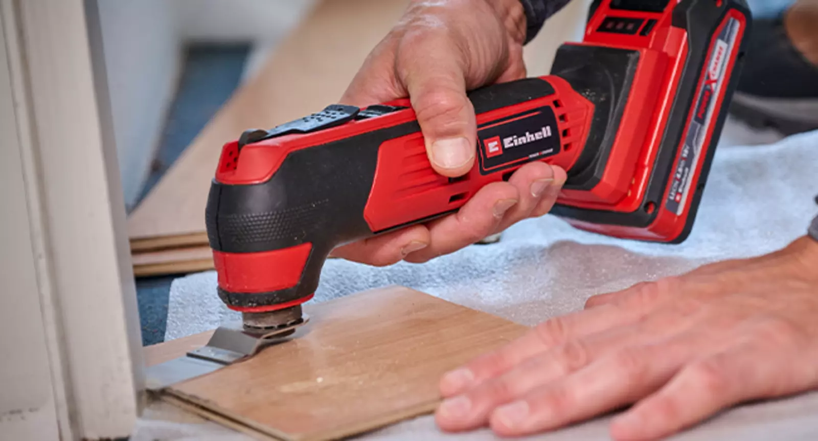 The Einhell cordless multifunctional tool TE-MG 18/1 Li Kit is used for sawing a piece of wood in a door frame.