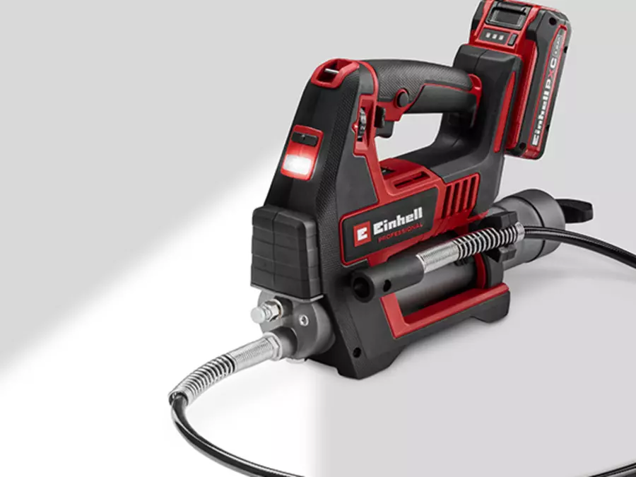 The Einhell cordless grease gun TP-GR 18/690 Li - Solo can be seen in operation, with the built-in LED light illuminating the work area.
