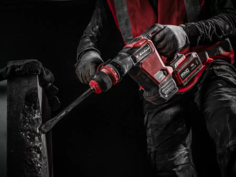 A worker in protective gear uses the Einhell cordless demolition hammer TP-DH 18/4 Li BL to break into concrete.