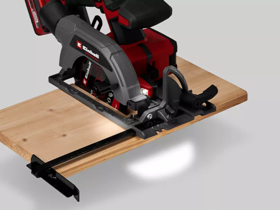 Die Einhell Akku-Handkreissäge TP-CS 18/136-C Li BL - Solo beim Sägen mit eingeschaltetem LED-Licht auf einer Holzplatte.