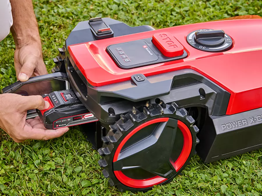Un hombre colocando la batería en el Einhell robot cortacésped FREELEXO 1000.