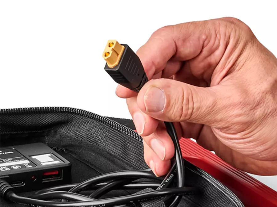 A hand holds an XT60 connector on the Einhell solar panel for connecting to compatible devices.