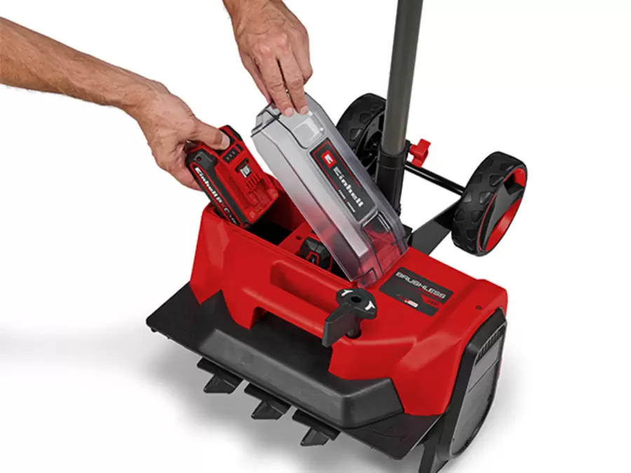 Due mani inseriscono una batteria PXC nel vano batteria aperto dello spazzaneve a batteria Einhell.