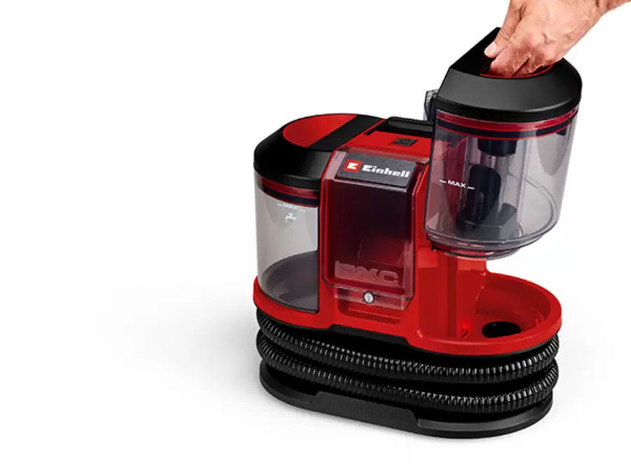 Eine Hand hebt den transparenten 1,1-Liter-Schmutzwassertank mit „MAX“-Markierung aus dem Einhell Akku-Waschsauger TE-SCL 18/1100 Li-S BL-Solo.