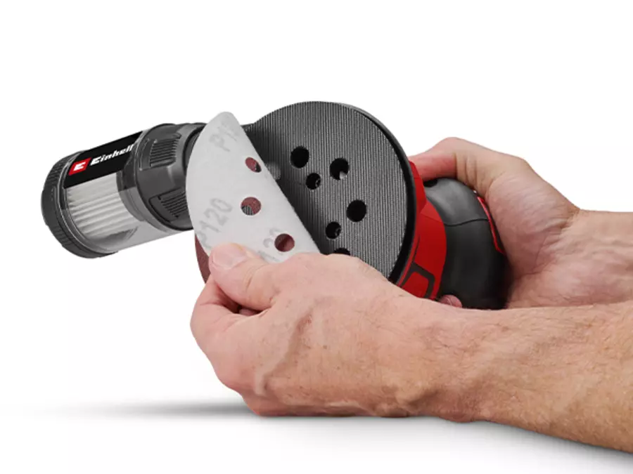 Hands attach a sanding sheet to the sanding disk of the Einhell cordless orbital sander TE-RS 18/28 Li - Solo using a hook-and-loop fastening system.