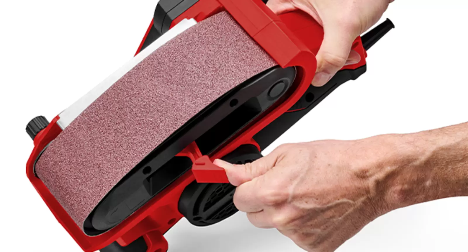Une personne actionne le levier de déverrouillage de la ponceuse à bande Einhell TC-BS 800 afin de changer la bande abrasive sans outil.