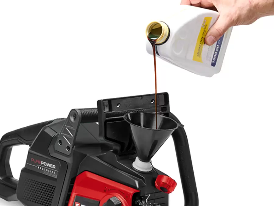 Hand filling the oil reservoir of the Einhell Professional 36V Brushless 400mm Chainsaw on a white background.
