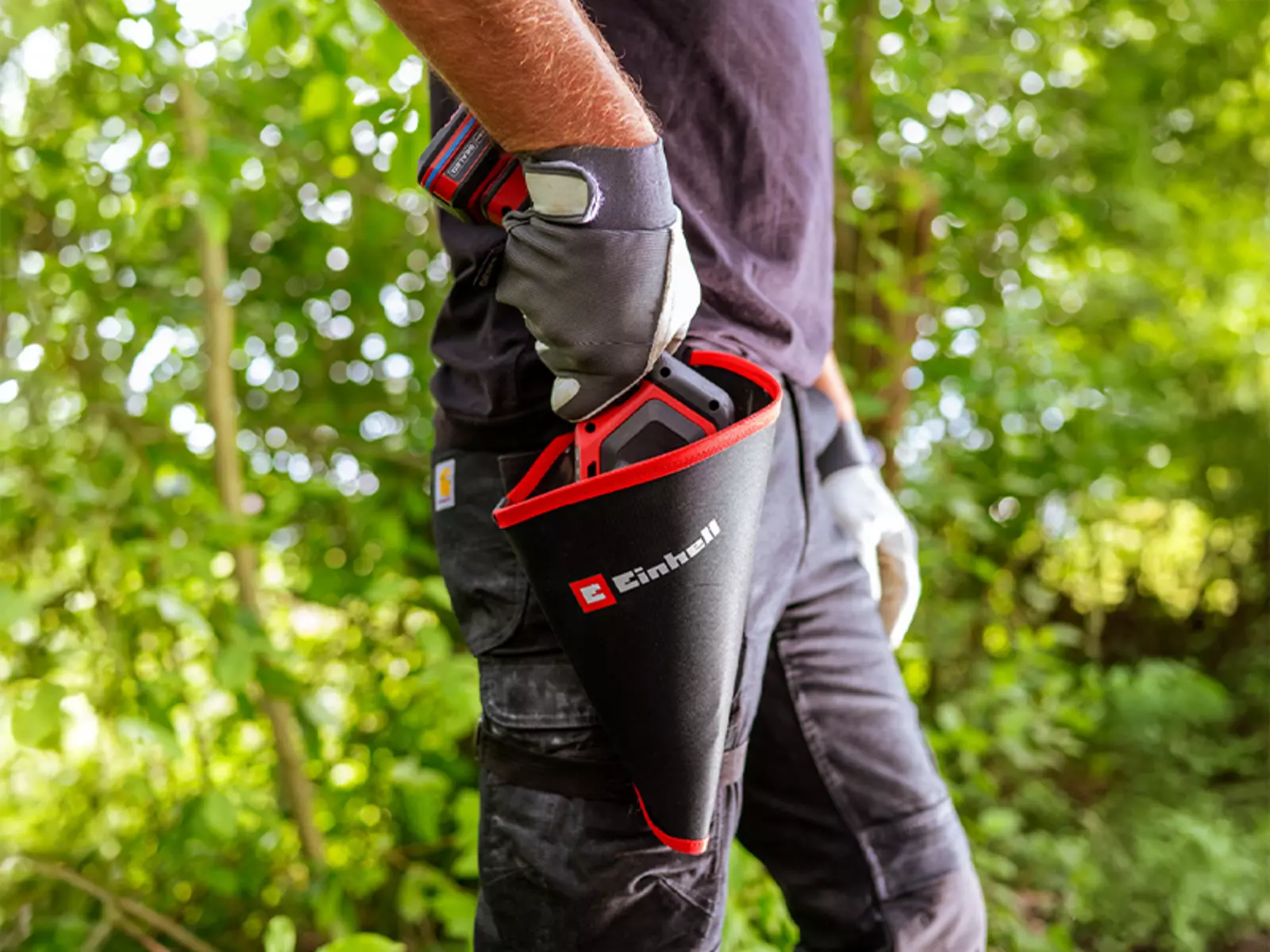 L’image montre une personne portant des gants qui range l’élagueuse sans fil Einhell GE-PS 18/15 Li BL dans l’étui fourni.