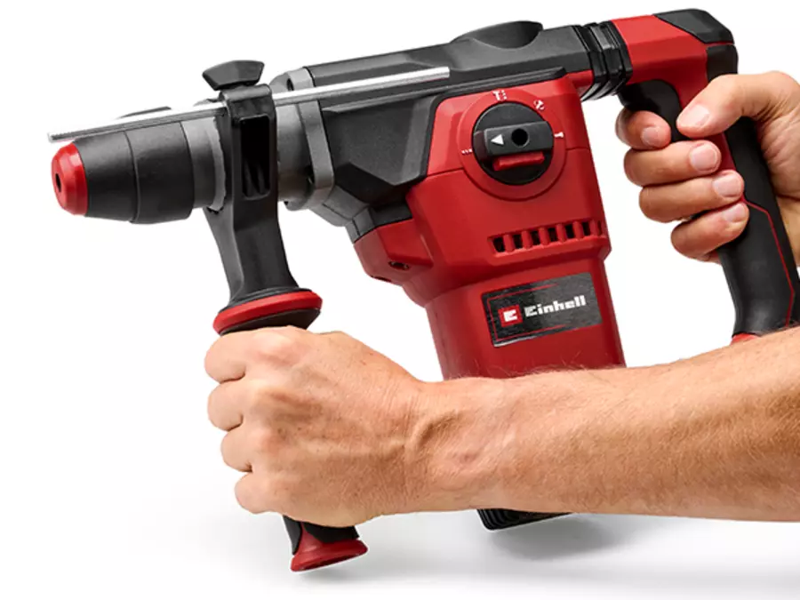 A man holds the Einhell rotary hammer TE-RH 34/6 4F +4 using the ribbed auxiliary handle for secure grip.
