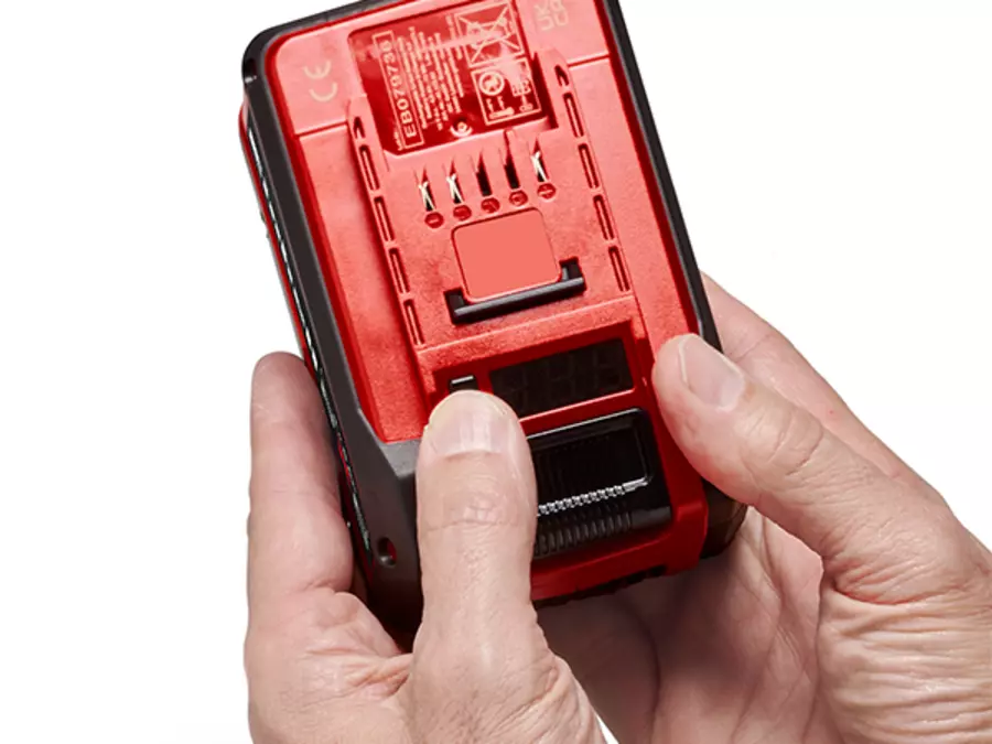 The Einhell Power X-Change battery, a hand presses the button to activate the charge level indicator.