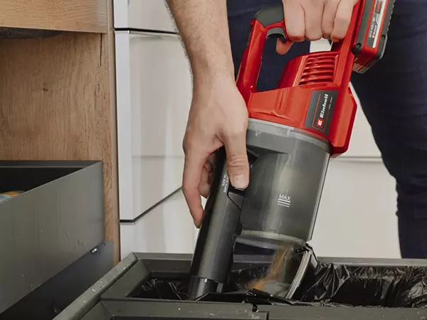Emptying the bagless dust container of the Einhell cordless stick vacuum cleaner TE-SV 18 Li over a bin.