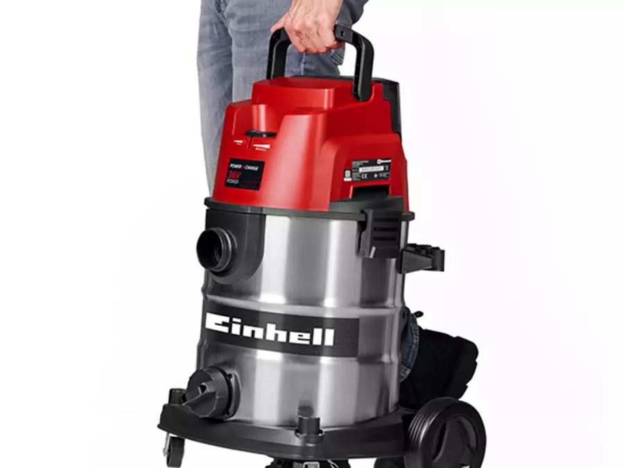 A person carries the vacuum cleaner by the top handle.